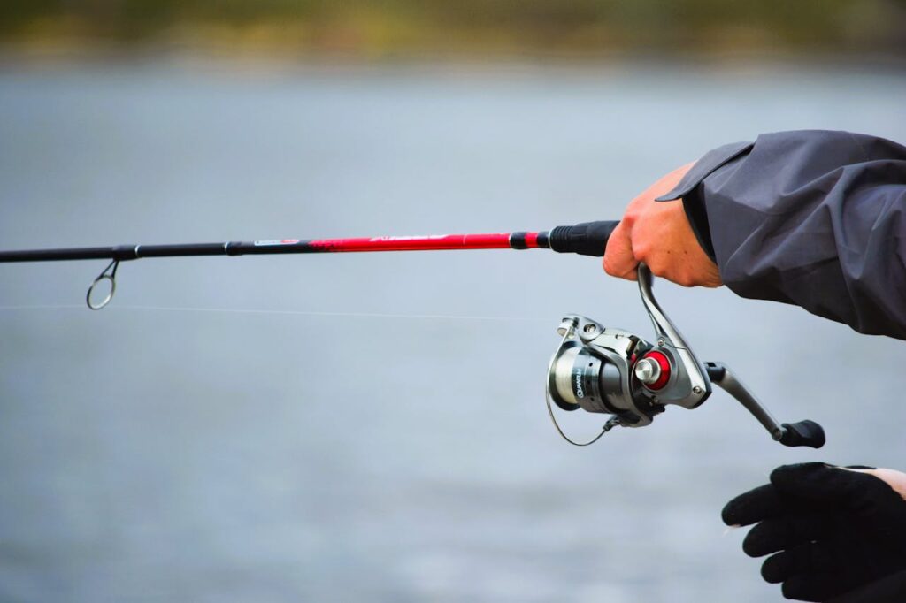 A person holds a fishing rod at a serene lake, capturing a peaceful moment.